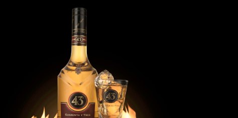 Fles likeur en glas op zwarte achtergrond met vuur